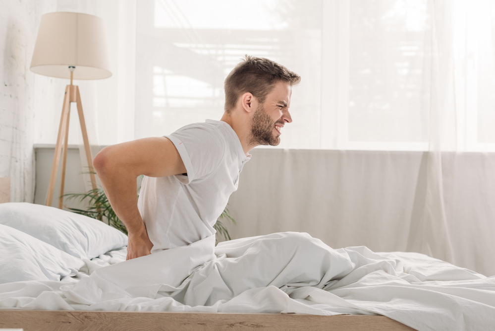 back-pain-mattress-bed-grimace-man