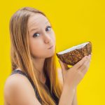 Oil Pulling Health Benefits Young woman doing oil pulling over yellow background